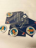 Group of four medallions, two sealed on blue backing cards, two loose