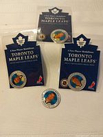 Three sealed Toronto Maple Leafs medallions on backing cards plus one loose medallion