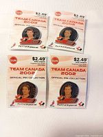 four sealed Team Canada 2002 pins on white surface