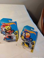 Both packaged Hot Wheels cars on table