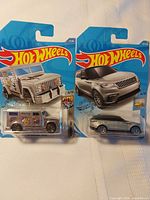 Front view of both carded Hot Wheels vehicles: Armored Truck and Range Rover Velar