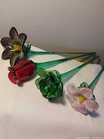 All four glass flowers laid out showing colours and green stems