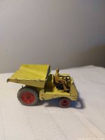 Left side view of yellow Dinky Supertoys dumper with driver and red wheels