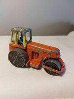 Left side view of orange Dinky Toys road roller showing full profile and driver