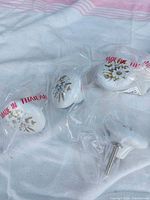 Four white ceramic drawer pulls still in plastic bags
