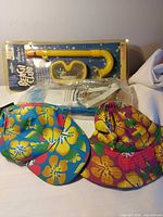 All three items grouped: sealed snorkel package and two floral hats