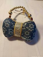 Front view showing denim fabric panels, rhinestone band and bead handle
