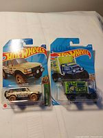 Two sealed Hot Wheels blister packs: Toyota Land Cruiser and Baja Hauler