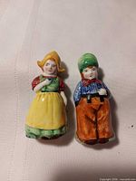 Front view of both ceramic shakers showing hand-painted figures