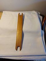 Full view of wooden weaving shuttle on white cloth
