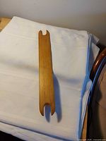 Full view of wooden weaving shuttle on white cloth