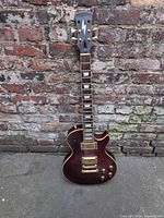 Full view of guitar leaning against brick wall