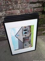 Stack of four black IKEA frames leaning against brick wall