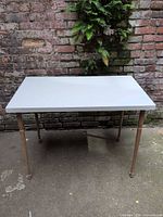 Full view of white rectangular Ikea table against brick wall