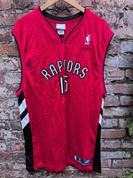 Full front view of red Raptors #15 Reebok jersey on hanger