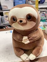 Front view of brown and cream sloth plush
