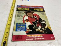 Front cover showing full magazine with tape measure for scale