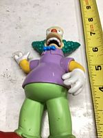 Front view of Krusty the Clown figure beside ruler