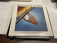 Front sleeve of The Fixx "Reach the Beach" LP on top of stack