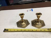 Both brass candlesticks shown with tape measure indicating size