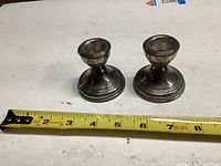 Two silver-plated candlesticks shown with tape measure for scale