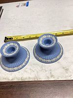 Pair of light blue Wedgwood candlesticks beside tape measure
