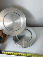 Stack of silver charger plates showing brushed finish and size