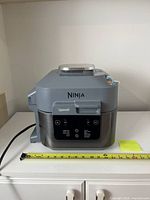 Front view of Ninja Speedi air fryer with measuring tape for scale