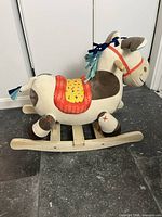 Side view of plush rocking horse showing fabric body, saddle, wooden rocker base