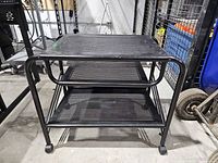 Front view showing full cart, three shelves, casters