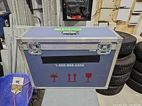 Front view of blue flight case showing latches, handle cutout, caution graphics and overall wear