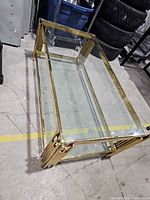 Oblique view of brass and glass coffee table showing full structure and lower shelf