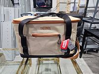 Front view of Thermos beige soft cooler with strap and tags attached