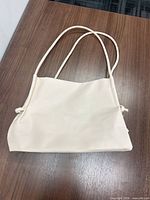 Front view of cream faux leather shoulder handbag on table