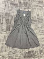 Full view of black sleeveless empire waist dress laid flat