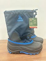 Side view of both navy/black Kamik snow boots with tag attached