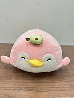 Front view of pink penguin plush showing face and avocado accessory