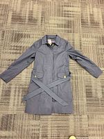 Full view of navy trench coat laid flat with belt visible