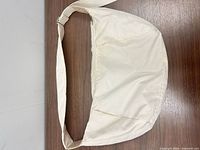 Full exterior view of off-white nylon crossbody bag with adjustable strap