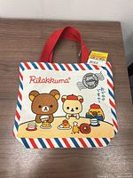 Front view of tote showing graphic, handles and tag