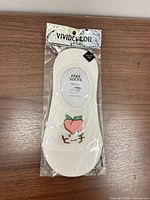 Front of packaged white sock showing VIVIDCOLOR branding and peach embroidery