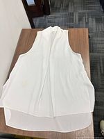 Full front view of white sleeveless draped collar blouse showing overall style and hem