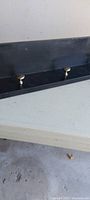 Top view of black shelf showing four metal knobs and interior surface