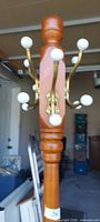 Top section showing brass hooks with white ball ends mounted on wooden column