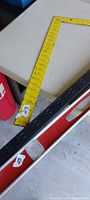 Yellow framing square, red level, portion of black power bar