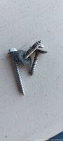 Close-up of three hex-head sheet-metal screws with washers