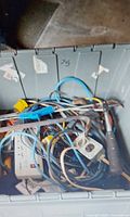 Grey tote holding extension cords, power strip, cables and metal bar