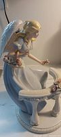 Front view of porcelain angel figurine with bench and flowers