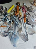 Pile of assorted flatware showing variety of pieces and handle styles
