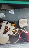 Tote containing power strips, cord reel, wooden shelf brackets, pink pot, silver tray partially visible